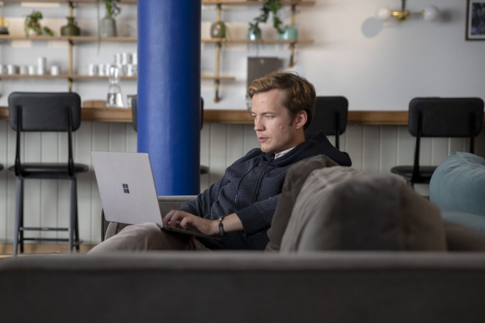 Iemand werkt geconcentreerd op een laptop in de lounge